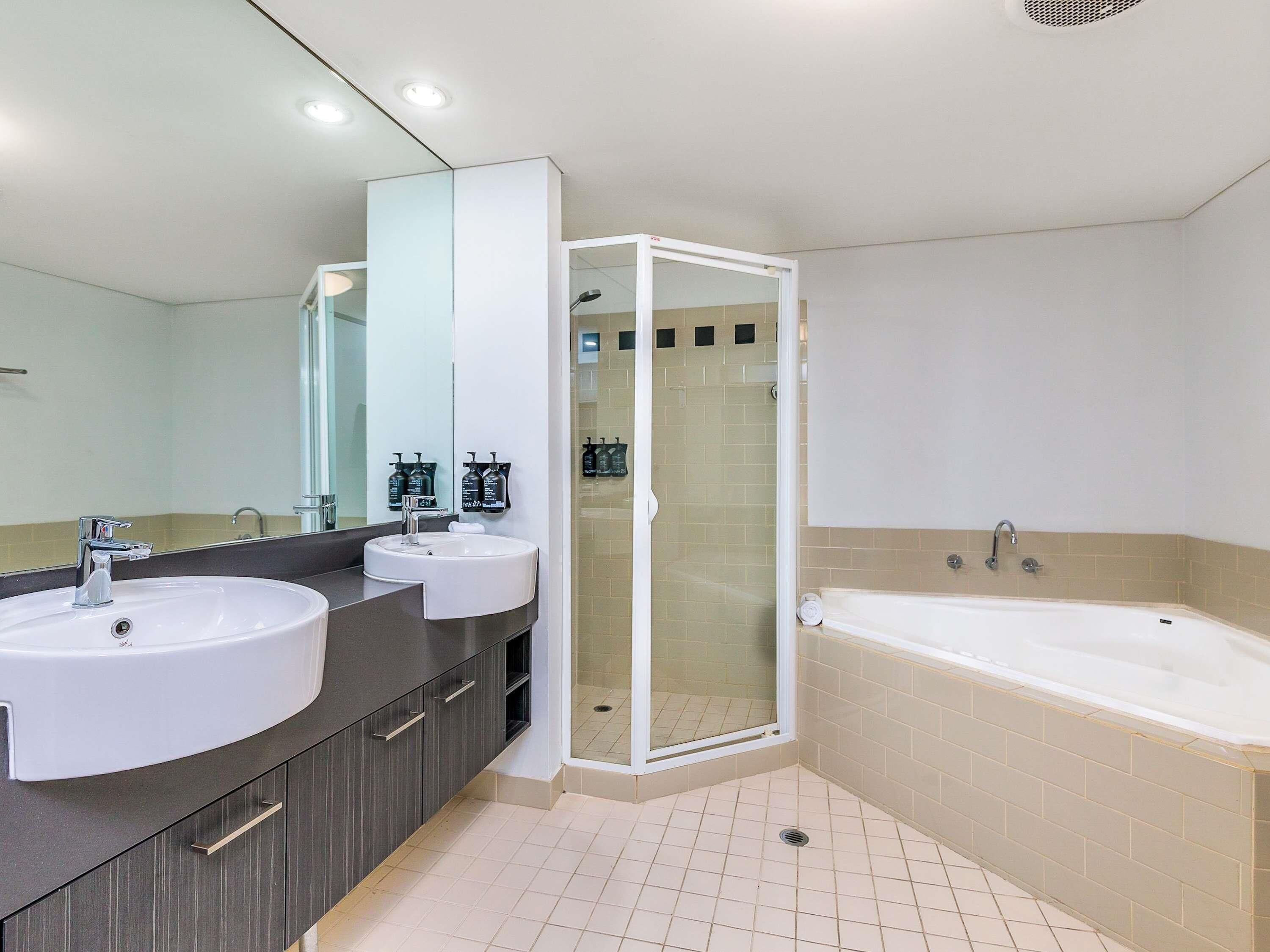 A modern bathroom with two sinks, a glass-enclosed shower, and a standalone bathtub.
