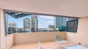 A balcony with two wicker chairs and a small table, overlooking a cityscape with high-rise buildings. - Mantra on Hay Perth (East Perth)