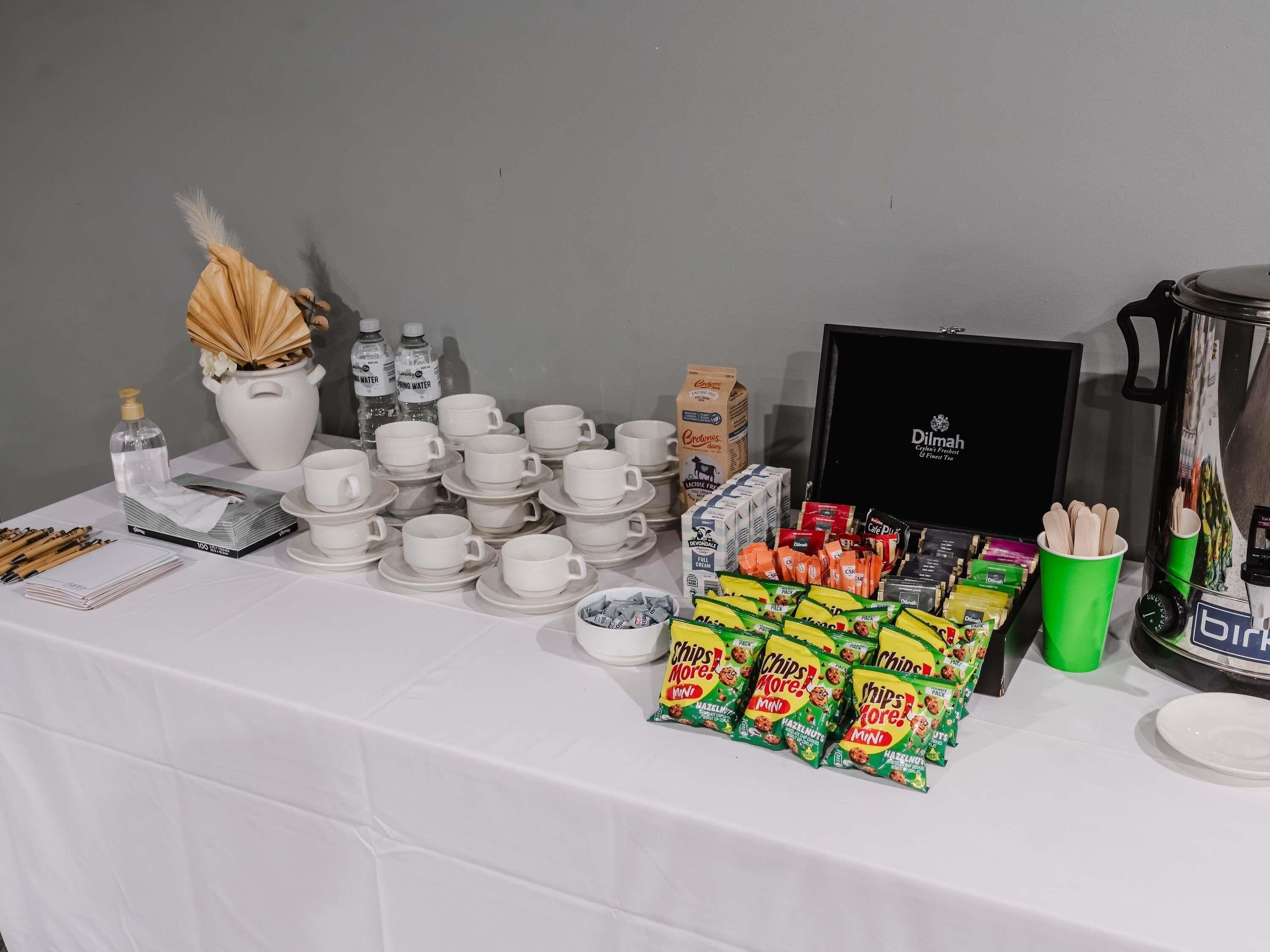 Une table dressée avec divers éléments pour le petit-déjeuner, notamment des tasses, des assiettes et des en-cas.