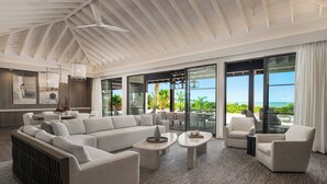 Un vaste espace de vie comprenant un grand canapé d’angle, deux tables basses et un coin salon avec des fauteuils.