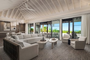 A spacious living area with a large sectional sofa, two coffee tables, and a seating area with armchairs.