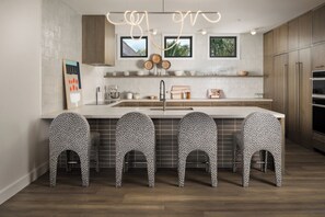 A modern kitchen with a central island, bar stools, and a backsplash of white tiles.
