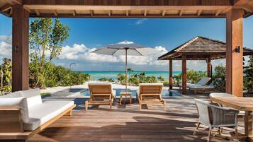 Relax in a serene oceanfront lounge with comfortable seating and a wooden table.