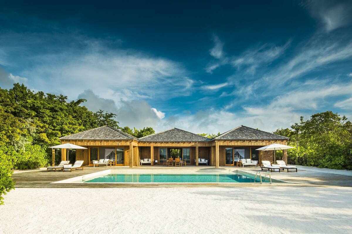 A resort with a pool, lounge chairs, and a wooden building with large windows.