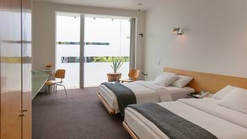 Habitación de hotel con dos camas, un escritorio, una silla y vistas al exterior.
