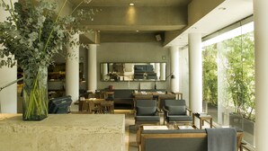 A spacious living area with a modern kitchen in the background, large windows, and a vase with flowers on a table. - Habita, Mexico City, a Member of Design Hotels (Mexico City)