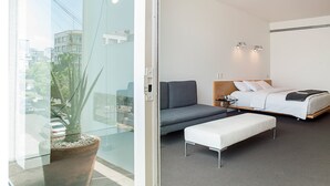 A modern hotel room with a bed, a sofa, a small table, and a potted plant. - Habita, Mexico City, a Member of Design Hotels (Mexico City)