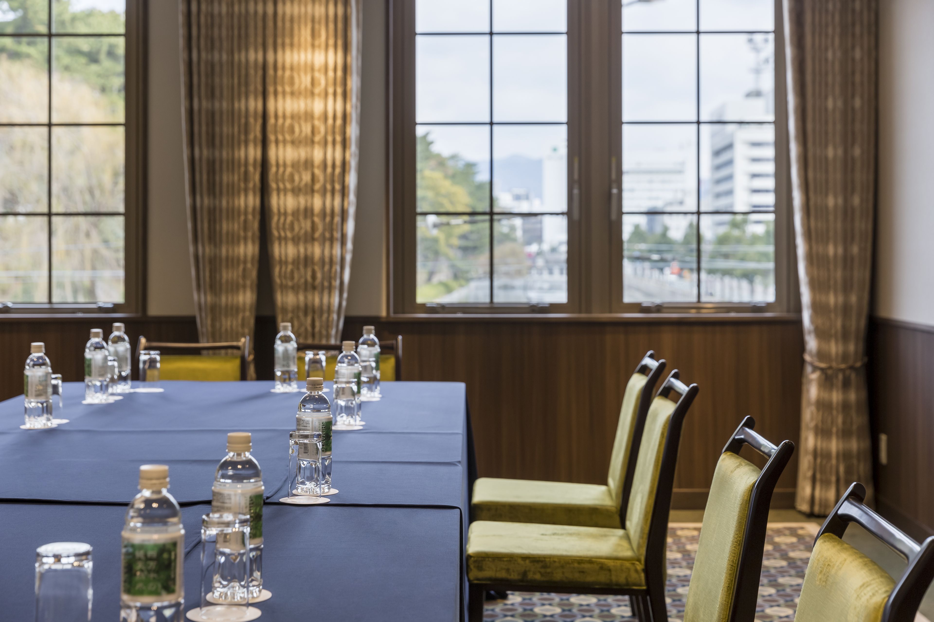 Une salle de conférence avec une longue table, des chaises, des bouteilles d’eau et des verres.