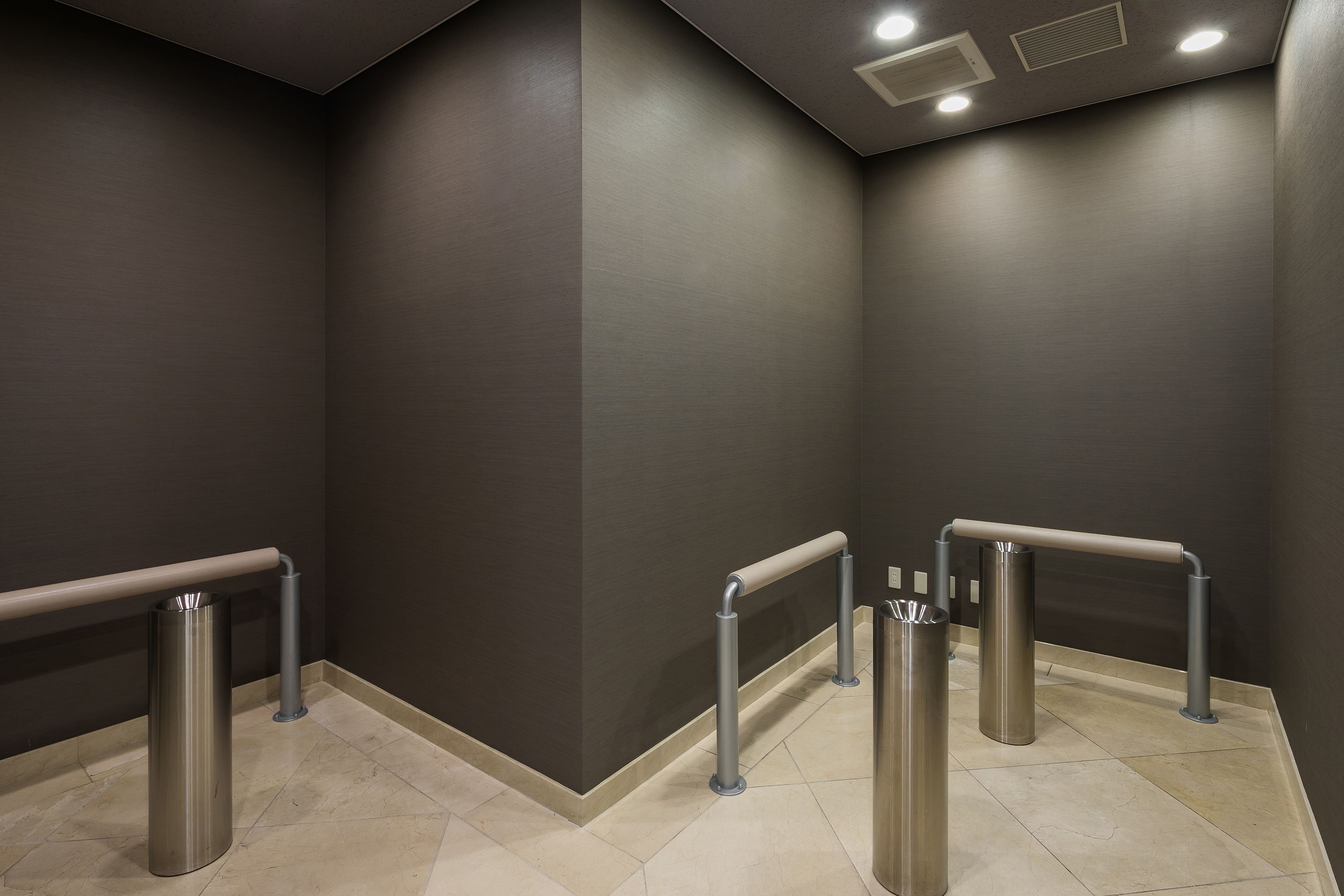 A modern elevator area with metallic handrails and a tiled floor.