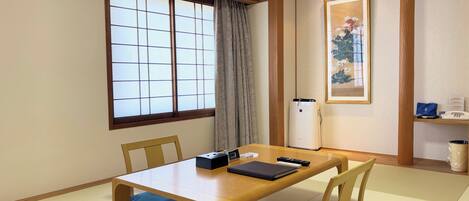 A traditional Japanese-style room with tatami flooring, a low wooden table, and a shoji screen window.