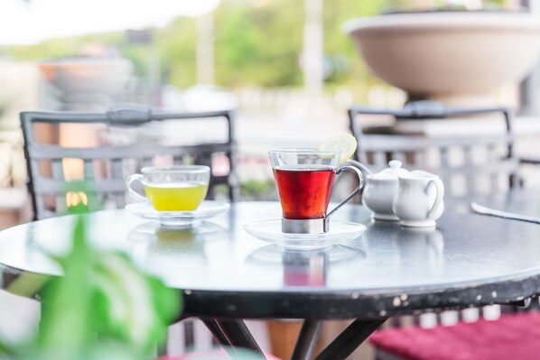 Una mesa redonda con una tetera de vidrio, una taza de vidrio con una rodaja de limón y una taza amarilla.