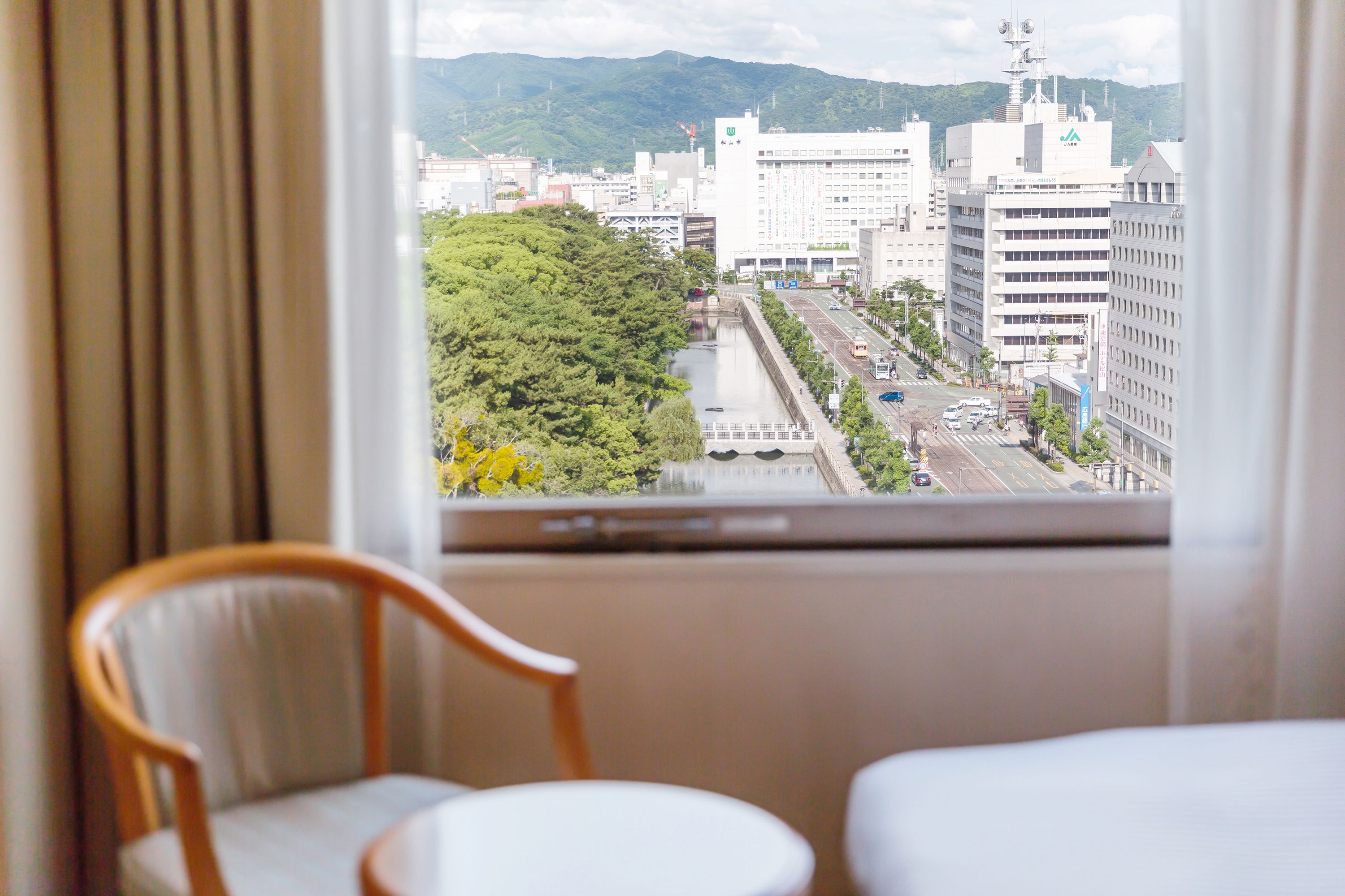 Habitación de hotel con vista a un paisaje urbano, que incluye edificios y un río.