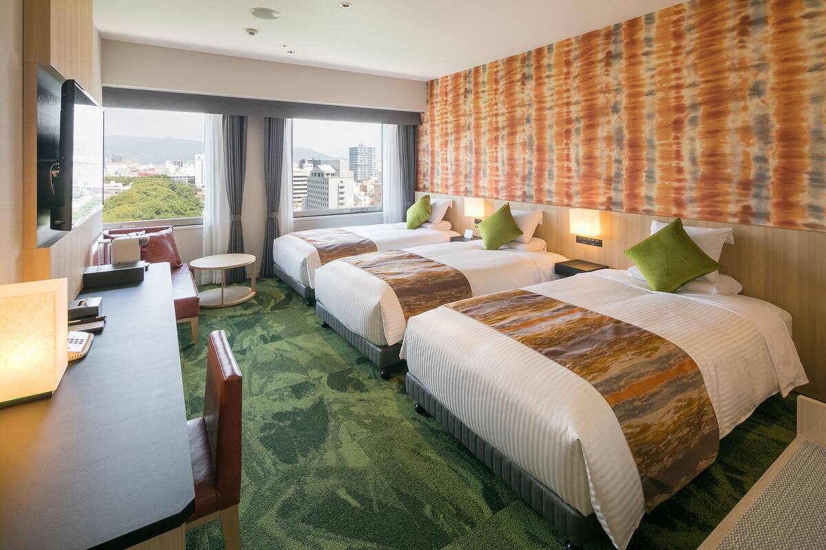 Une chambre d’hôtel avec deux lits, un bureau et une vue sur la ville.