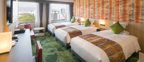 A hotel room with two beds, a desk, and a view of the city.