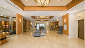 A spacious lobby with a reception desk, seating area, and a large chandelier.
