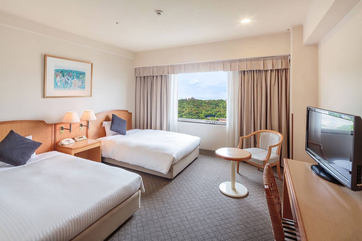 Une chambre d’hôtel avec deux lits, une télévision, un bureau et une chaise.