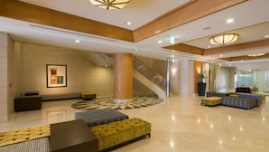 A spacious lobby with a central column, a staircase, and seating areas.