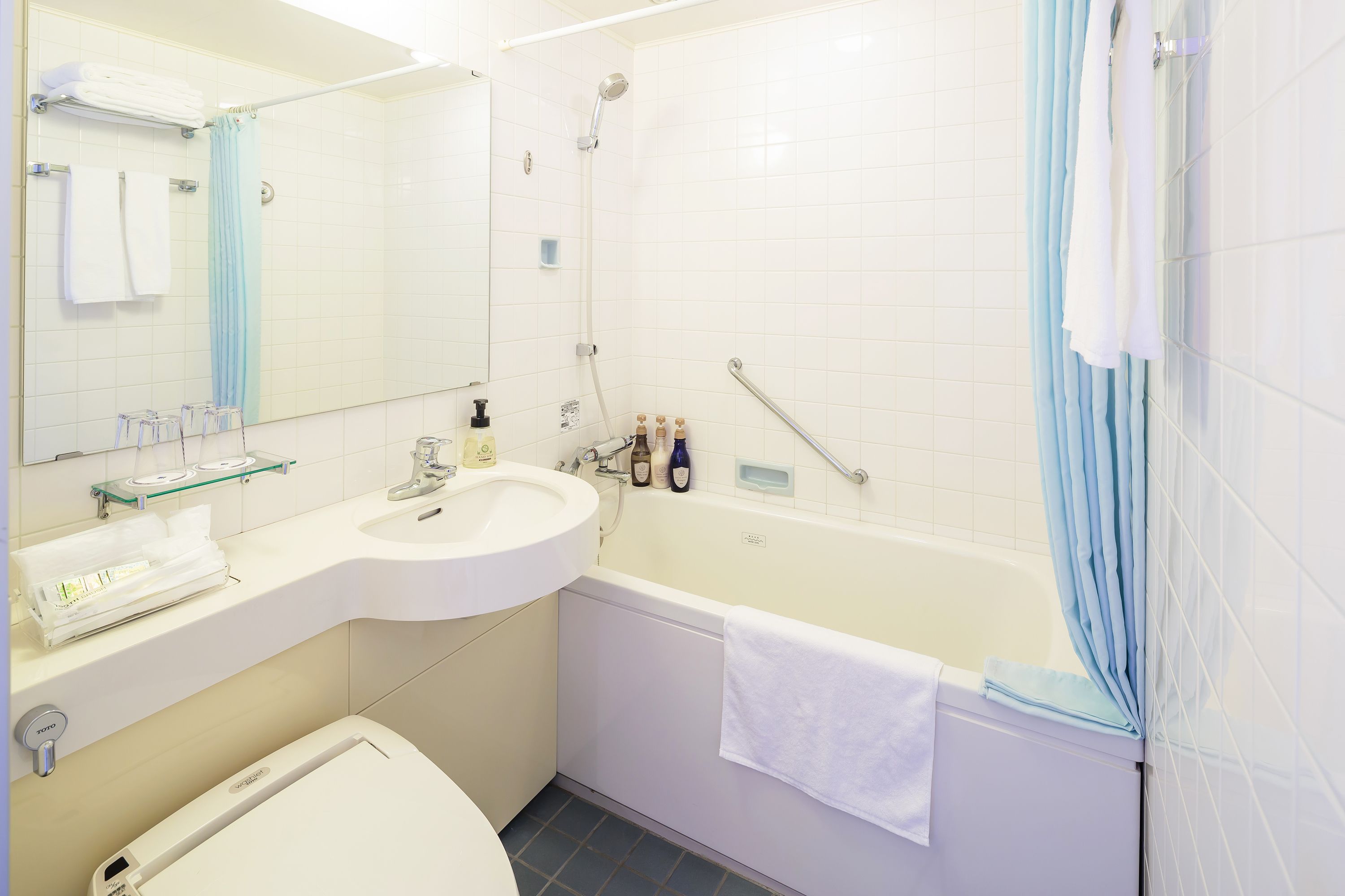A bathroom with a sink, mirror, and bathtub.