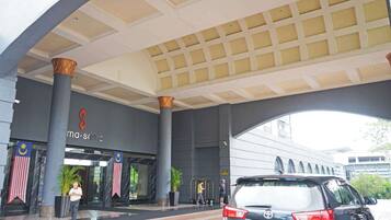 A modern hotel entrance with a large overhang, prominent pillars, and a sign reading 'ma-sama.'