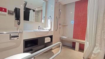 A modern bathroom with a toilet, sink, mirror, shower, and a red-tiled wall.