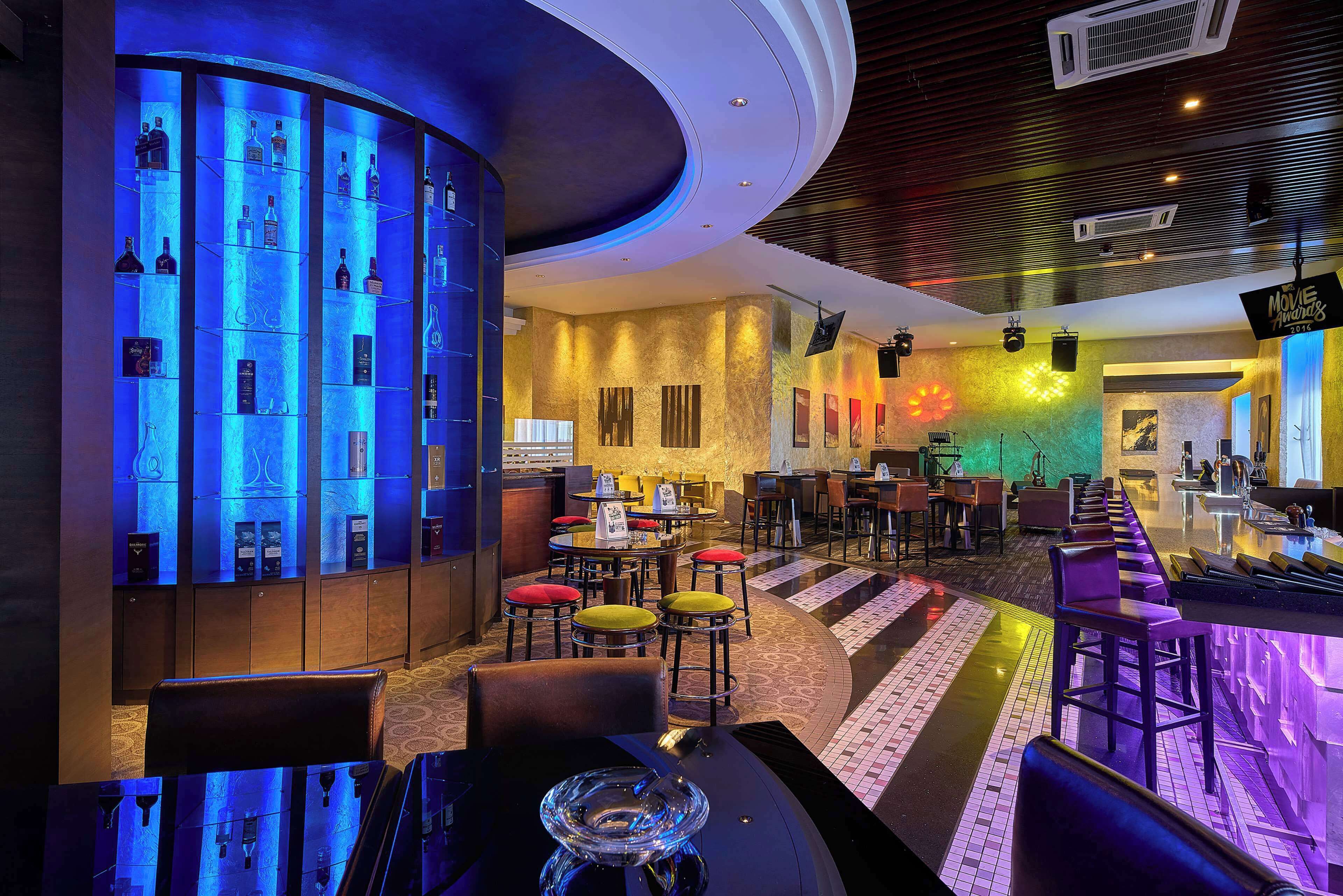 A bar area with a curved counter, multiple seating options, and a display of bottles.