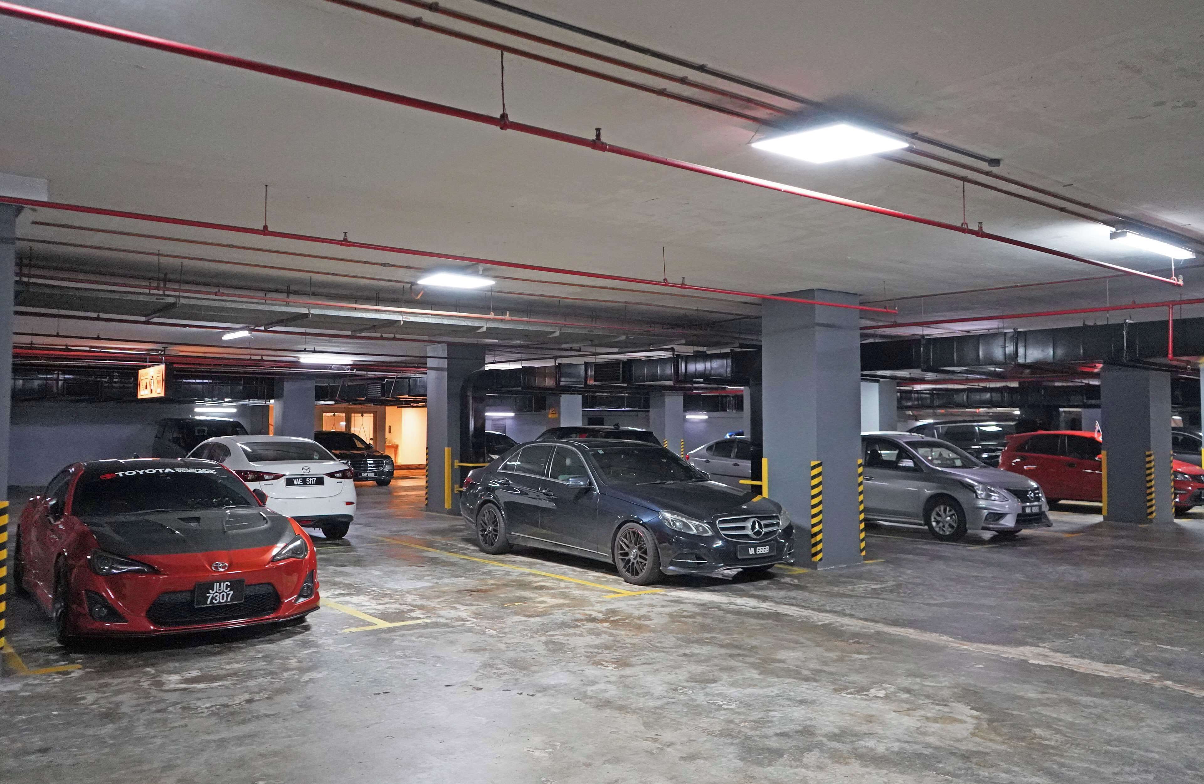 A multi-level parking garage with several cars parked, concrete pillars, and overhead lighting.