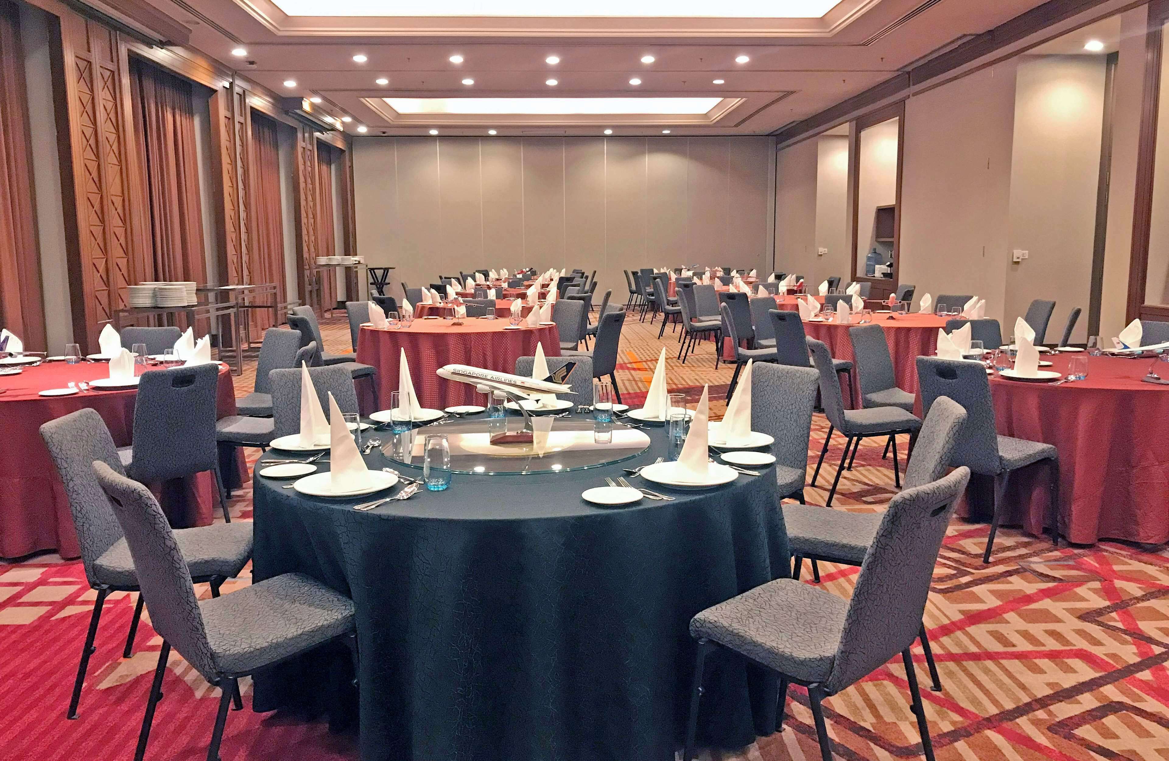 A conference room with round tables, chairs, and a buffet area.