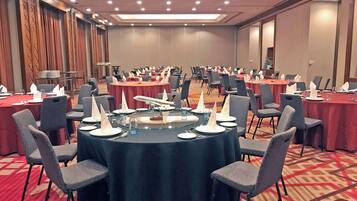 A conference room with round tables, chairs, and a buffet area.