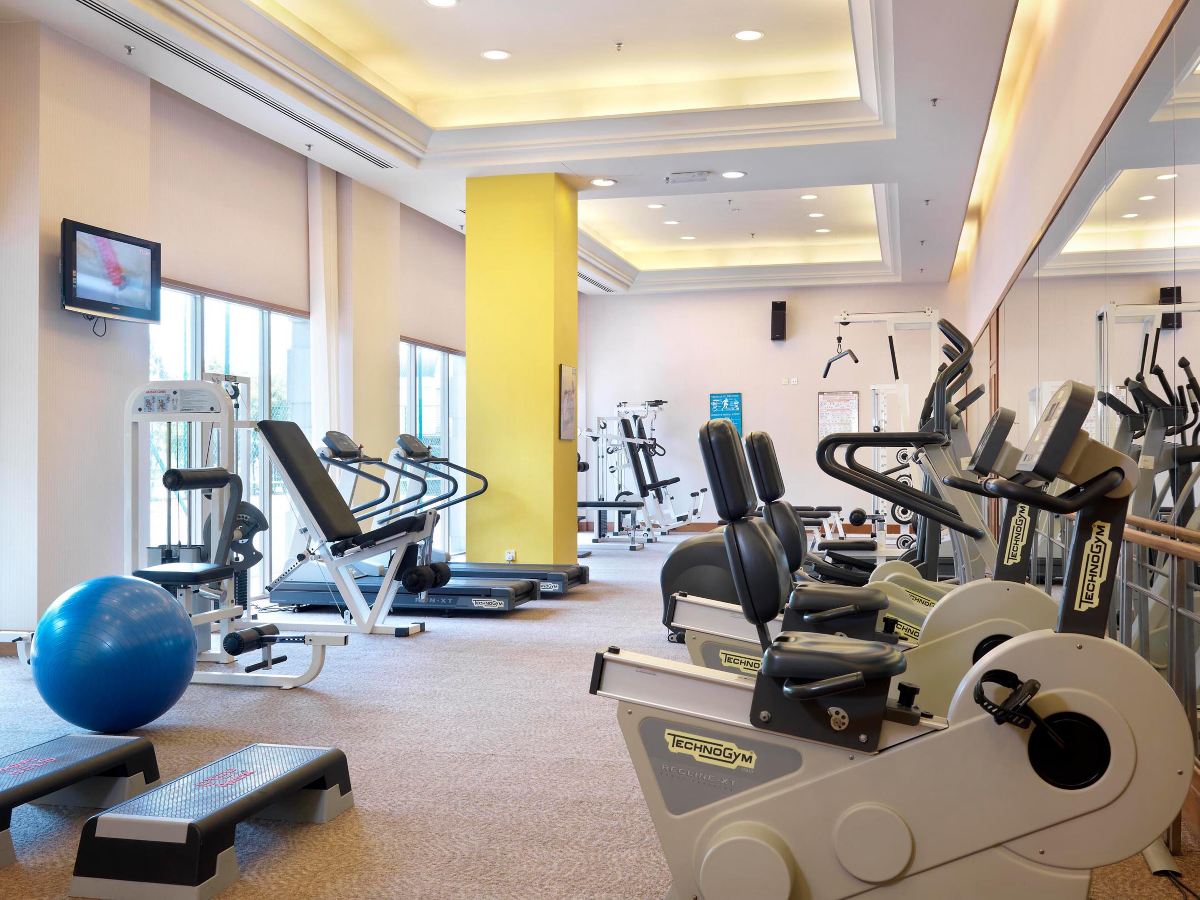 Ein Fitnessraum mit Laufbändern, Krafttrainingsgeräten und Übungsbällen.