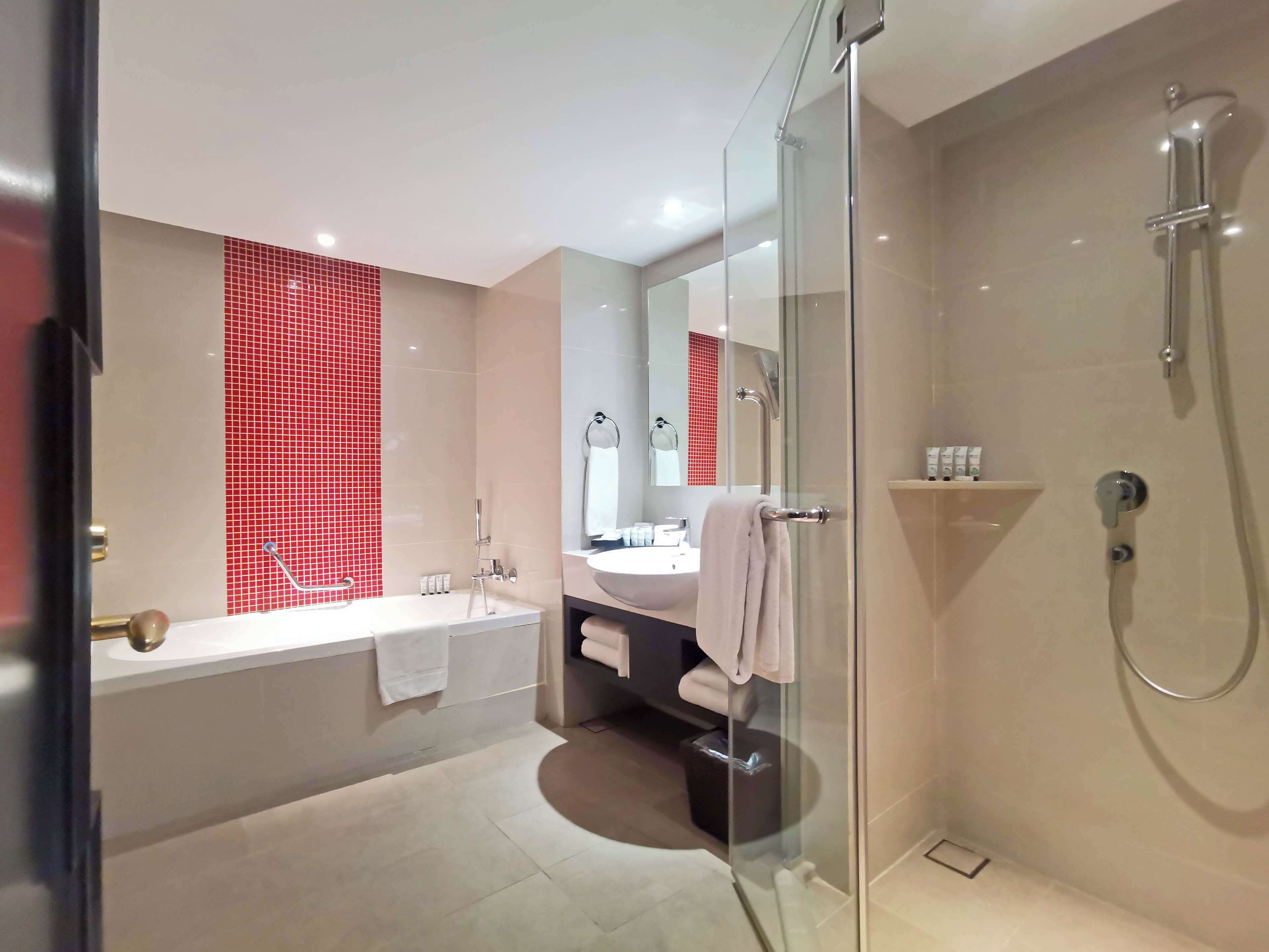 A modern bathroom with a glass shower enclosure, a large mirror, and a bathtub.