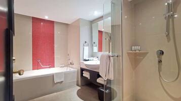 A modern bathroom with a glass shower enclosure, a large mirror, and a bathtub.