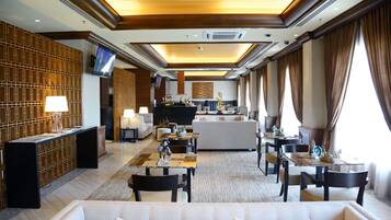 A hotel lobby with a reception desk, seating area, and a television screen.