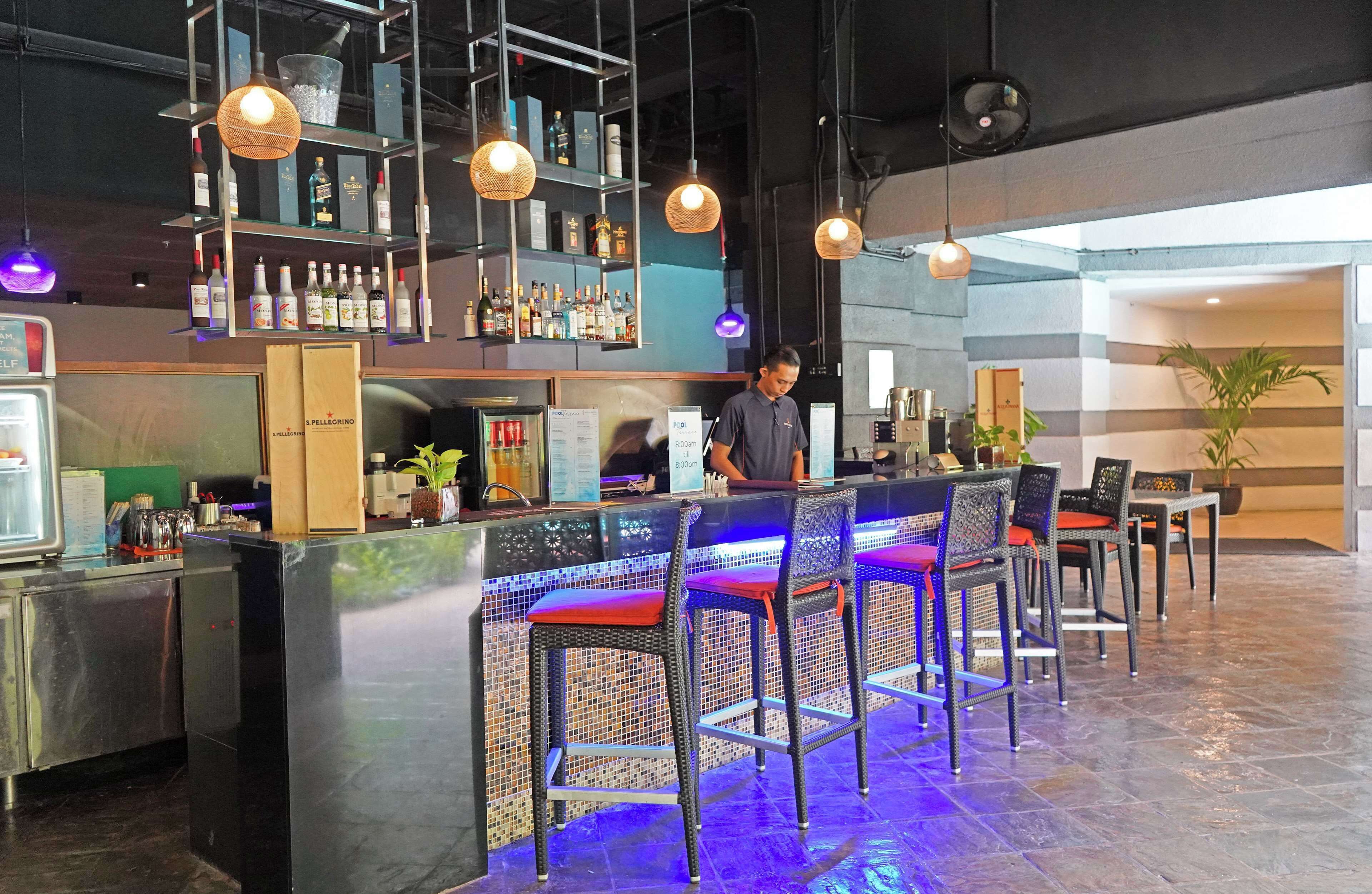 A bar area with a counter, bar stools, and shelves with bottles.