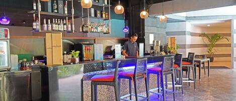A bar area with a counter, bar stools, and shelves with bottles.