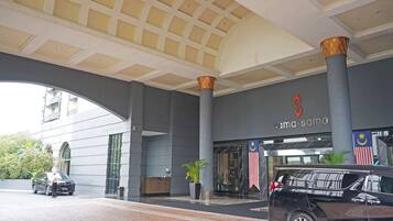 A hotel entrance with a large archway, a reception desk, and a parking area.