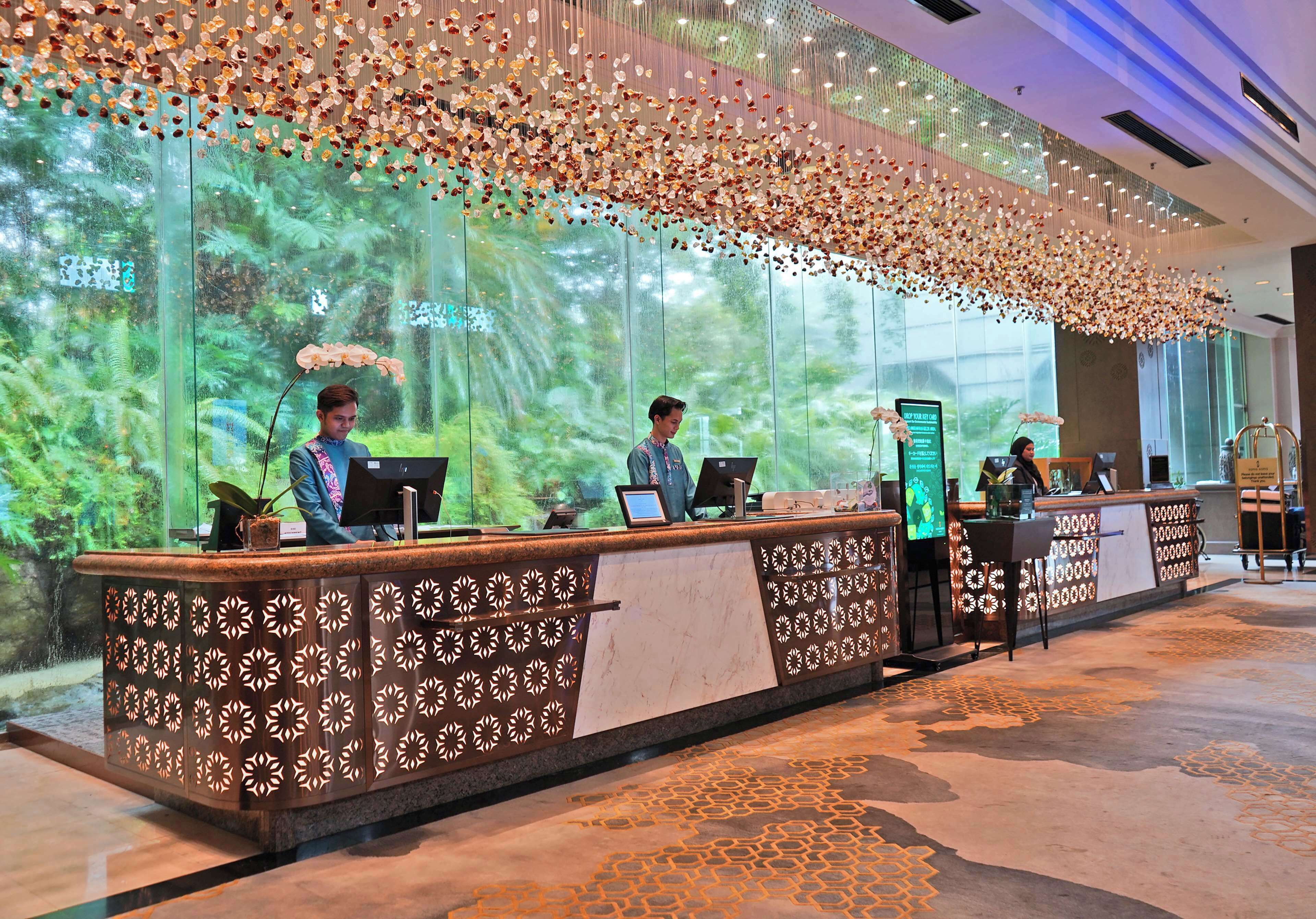 A reception desk with a patterned design, a large window with a view of greenery, and a decorative ceiling.