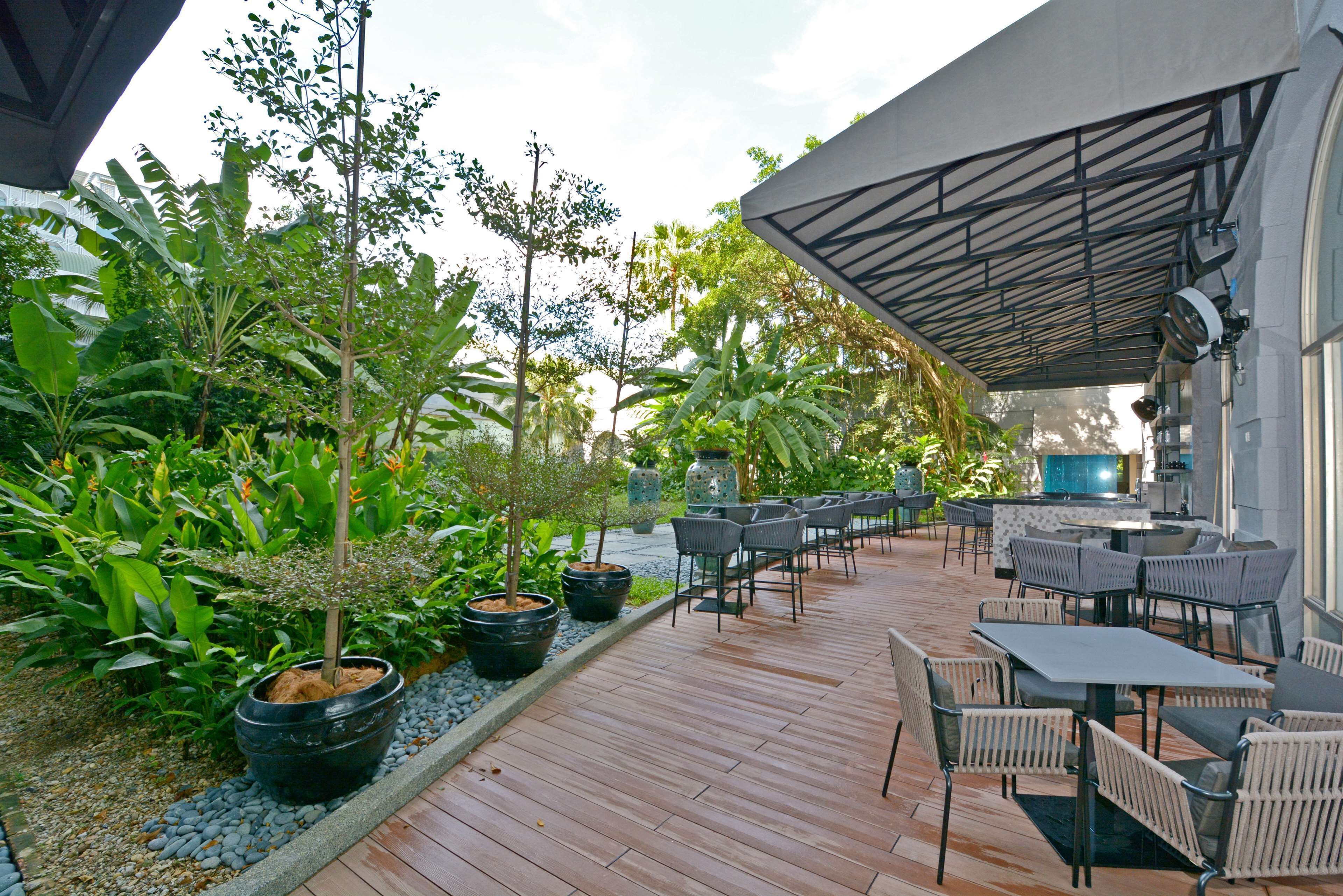 An outdoor patio area with wooden flooring, potted plants, and outdoor seating.
