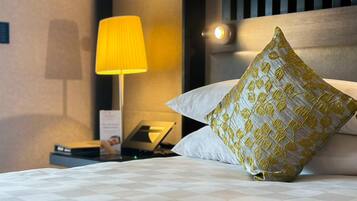 A hotel room with a bed, a nightstand, a lamp, and a pillow.