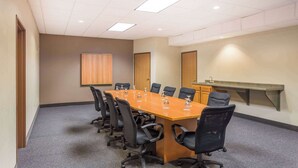 Un salón de conferencias con una larga mesa, sillas negras, una pizarra y un lavamanos.