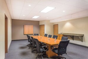 A conference room with a long table, black chairs, a whiteboard, and a sink. - Wyndham Garden Madison Fitchburg (Madison)