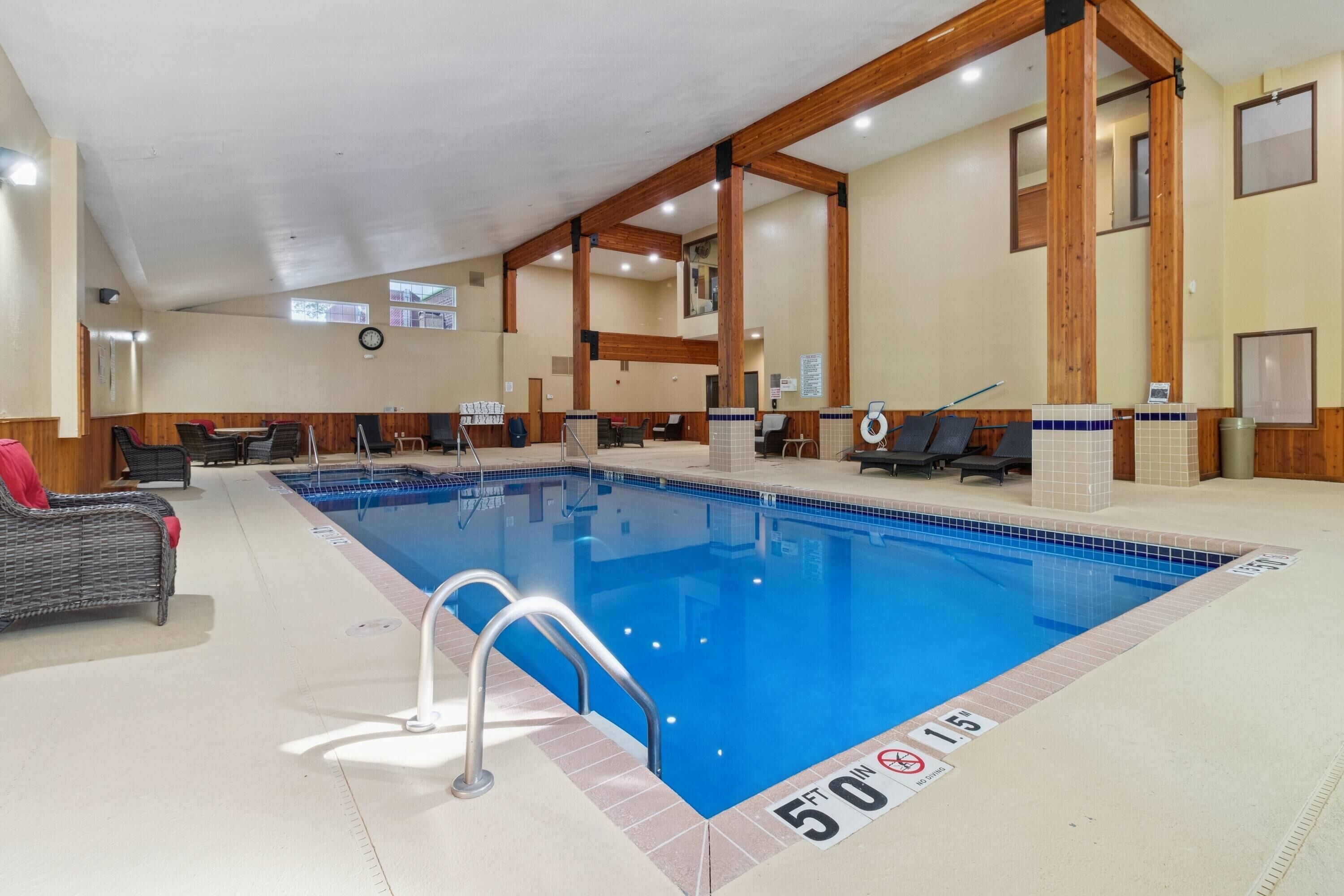 Una piscina interior con 15 metros de profundidad, vigas de madera y sillones de descanso.