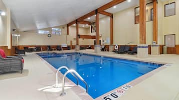 Una piscina interior con 15 metros de profundidad, vigas de madera y sillones de descanso.