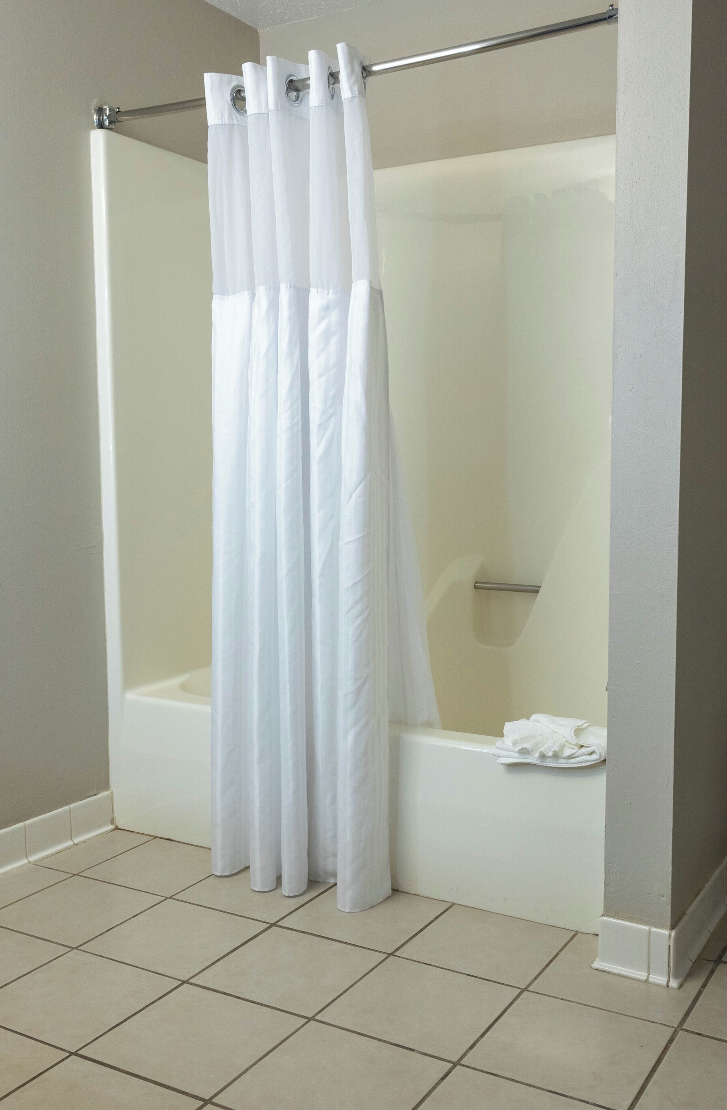 Un baño con cortina de ducha blanca, una bañera y un inodoro.