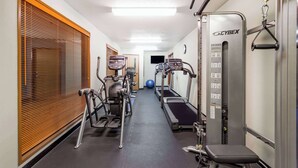 Un gimnasio con cintas de correr, elípticas y una banca.