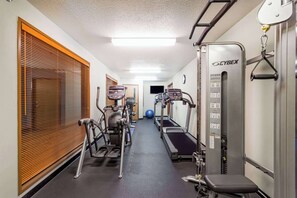 A gym with treadmills, ellipticals, and a bench. - Wyndham Garden Madison Fitchburg (Madison)