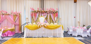 A wedding reception setup with a stage, tables, chairs, and floral decorations. - Wyndham Garden Madison Fitchburg (Madison)