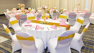 Ein runder Tisch mit weißen Tischdecken, goldenen Tischläufern und rosa Servietten.