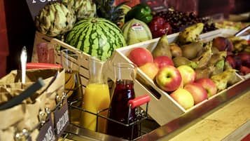 Una exhibición de frutas con diferentes tipos y un dispensador de jugo.