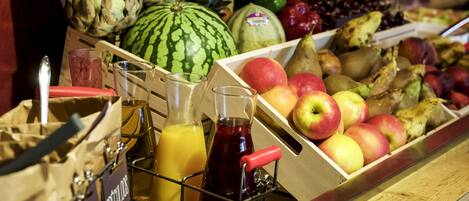 Una exhibición de frutas con diferentes tipos y un dispensador de jugo.