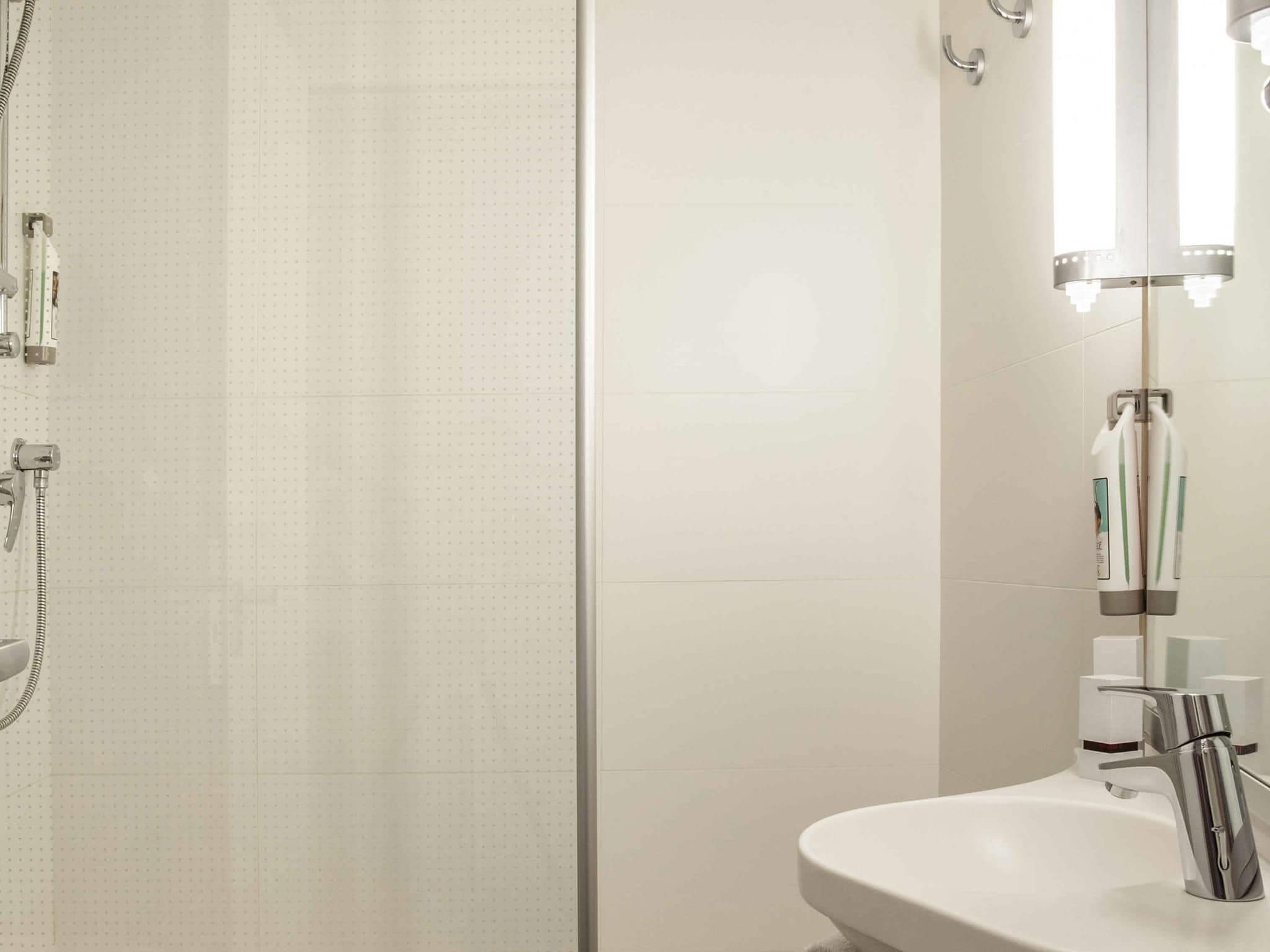 Une salle de bain moderne avec une douche, un lavabo et un miroir.